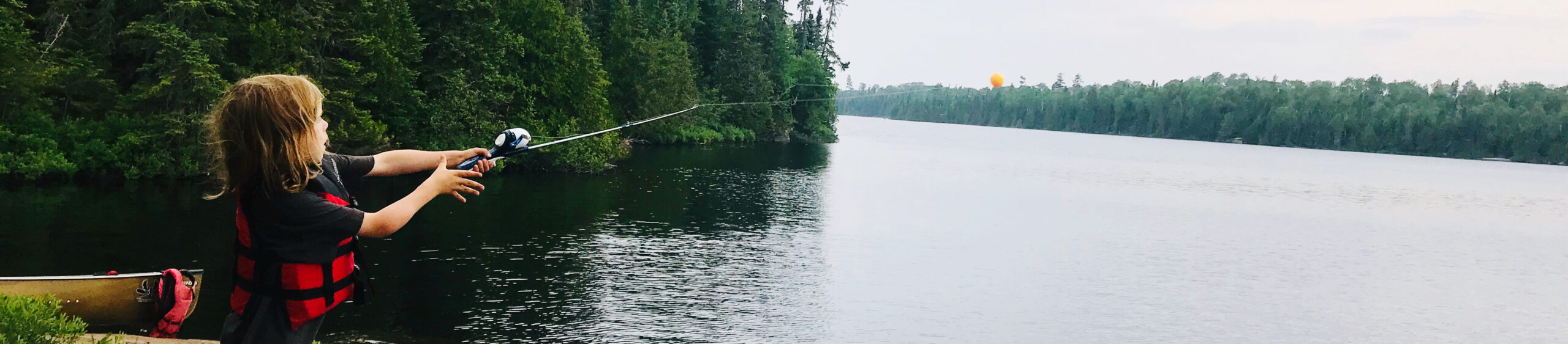 Boy Fishing While Standing By Lake