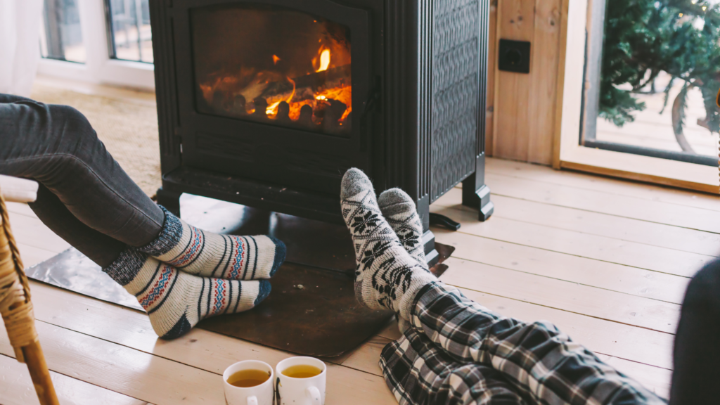 Couple warming up indoors next to a fireplace
